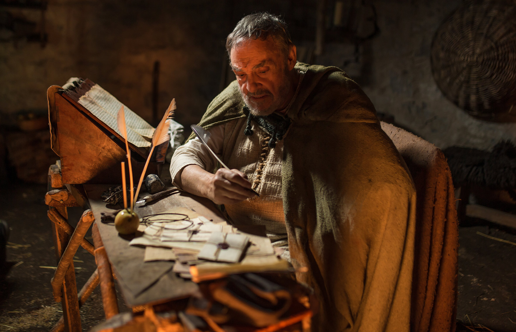 An older Patrick at desk writing letters.